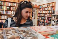 Caroline perches her sunglasses atop her head while looking at books in a bookstore. 