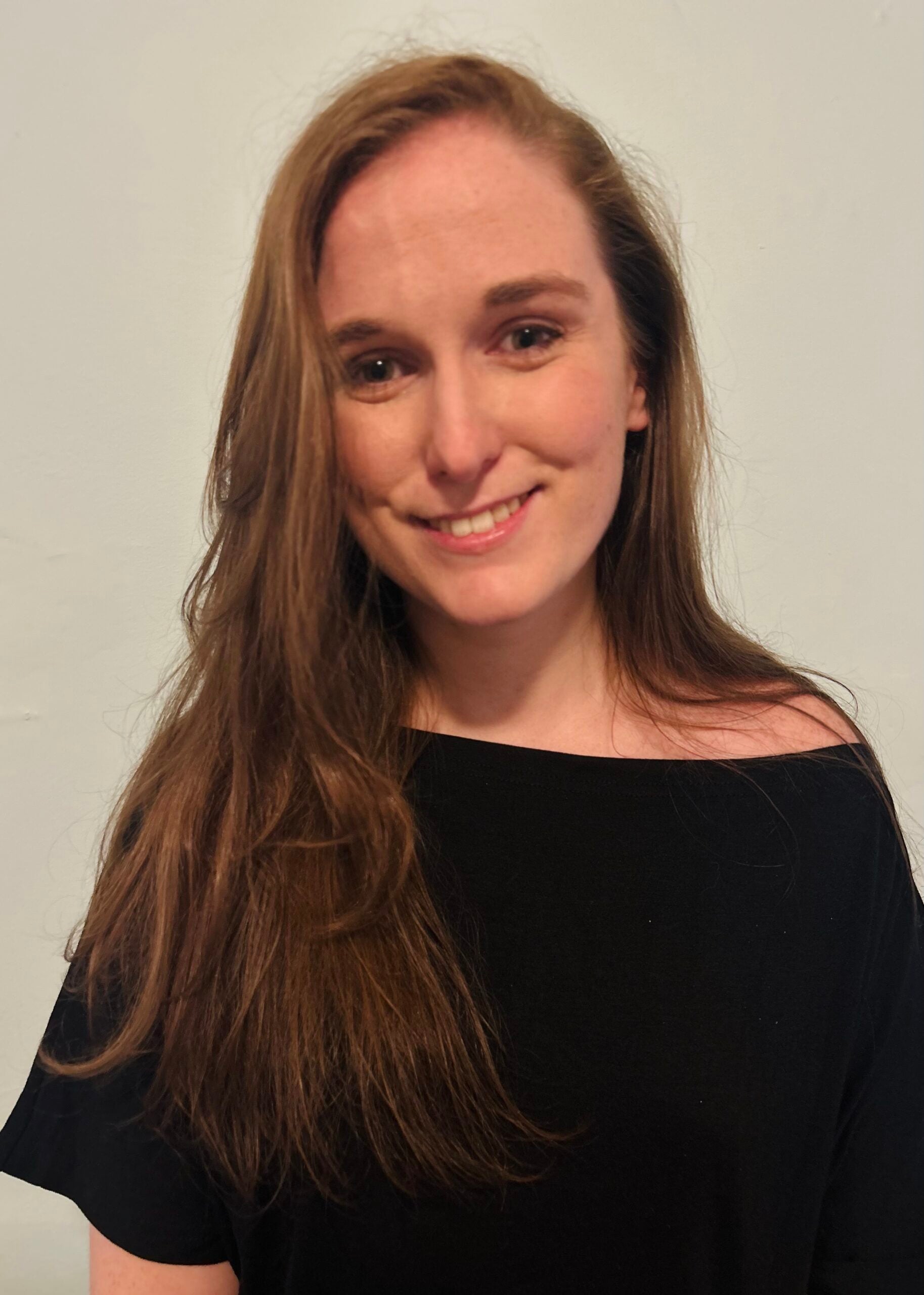 Colleen smiles at the camera while wearing a drapey black top. 