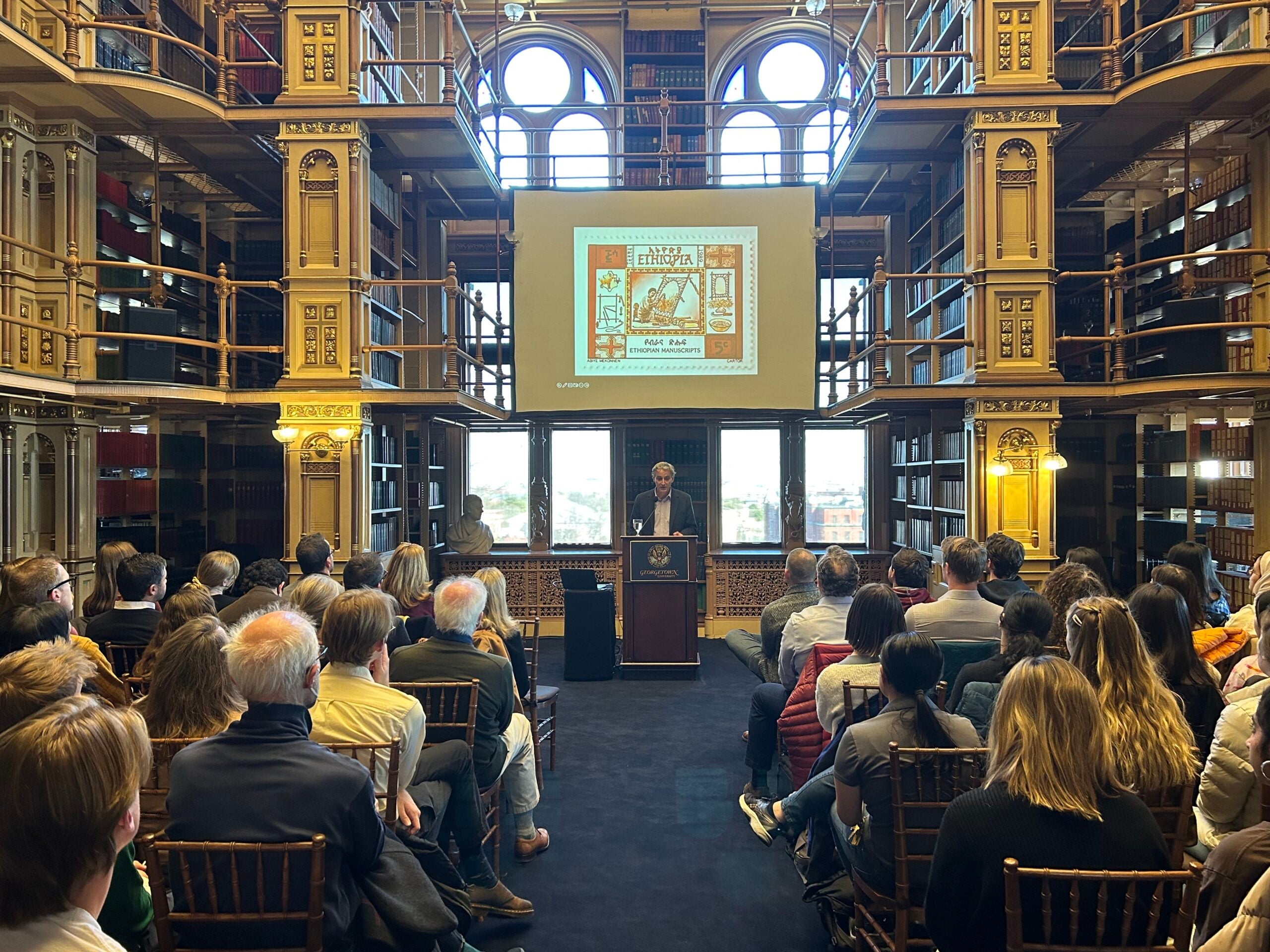 Bruce Holsinger presenting a lecture before a crowd