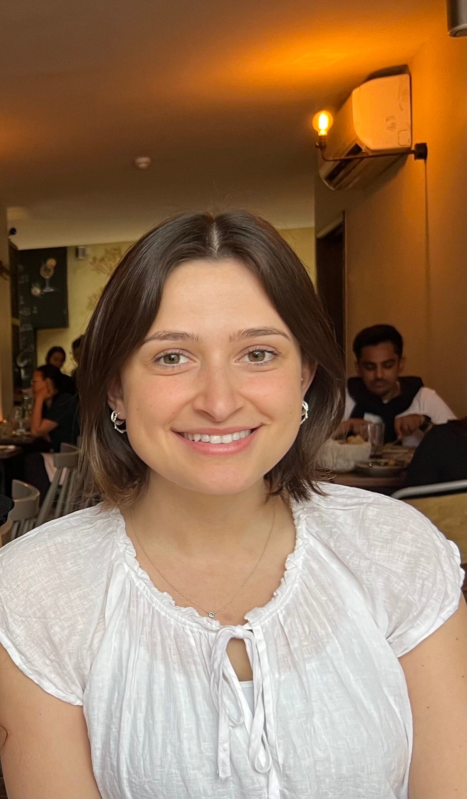 Lauren wearing a white blouse, her brown hair shortly above her shoulders, smiles at the viewer