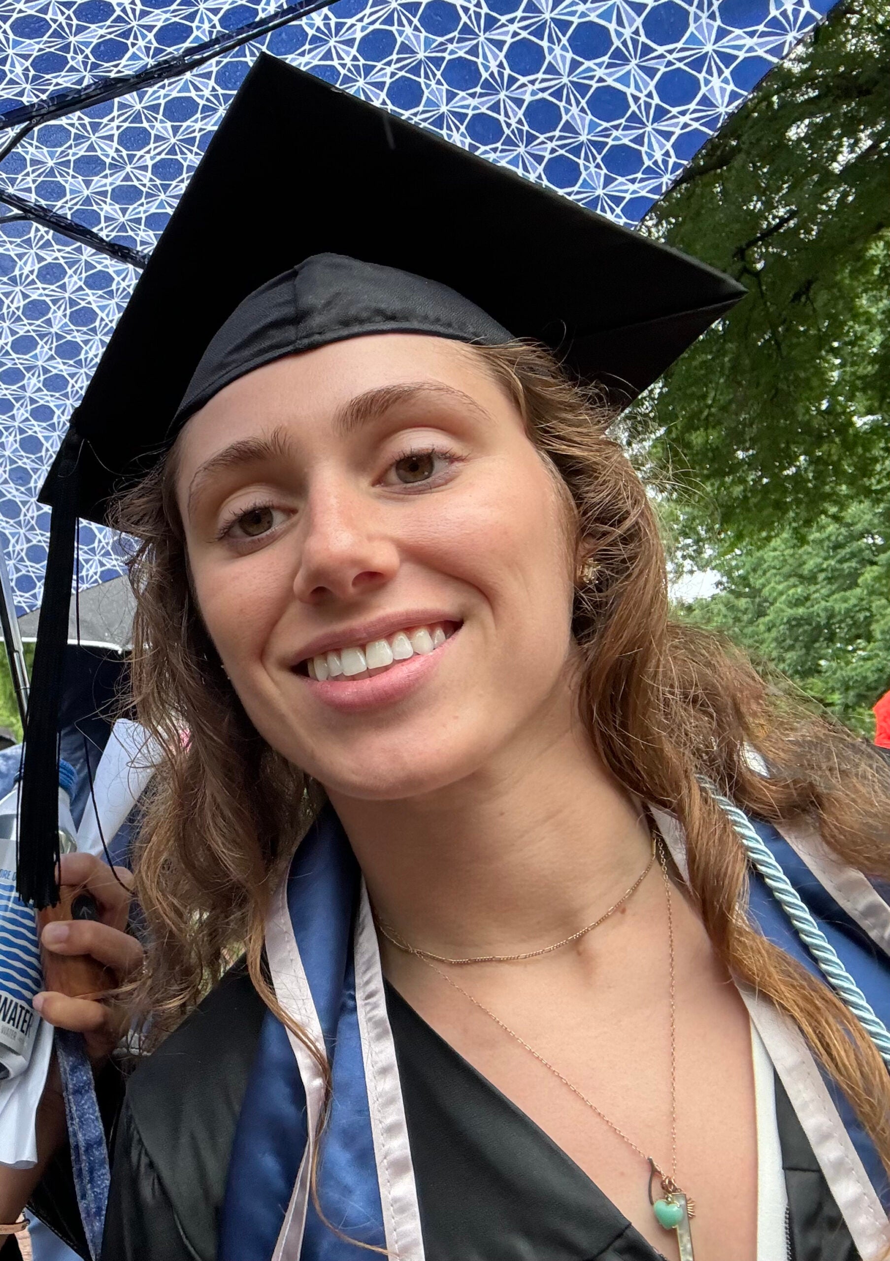 Gabby wearing her graduation garb smiles at the viewer