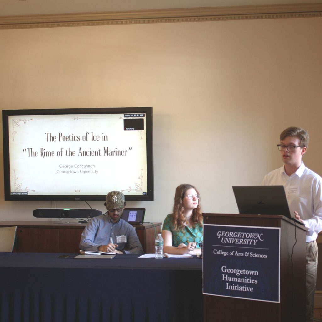 George Concannon, MA '26, stands behind a lectern delivering his conference paper on "The Poetics of Ice in 'The Rime of the Ancient Mariner'" fellow panel members sit behind him and listen intently