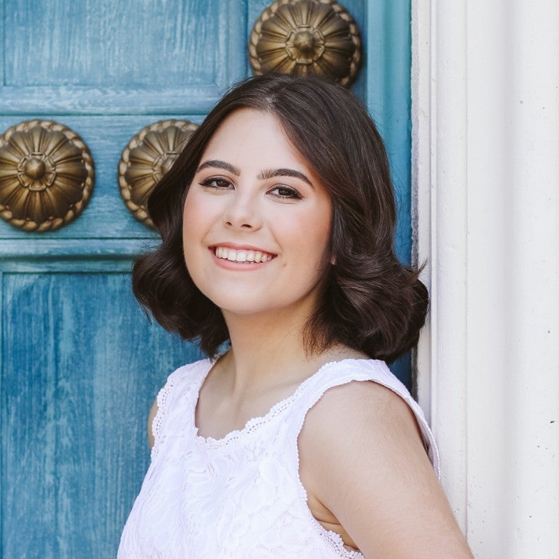 A headshot of Camille Deschapelles before a green door.