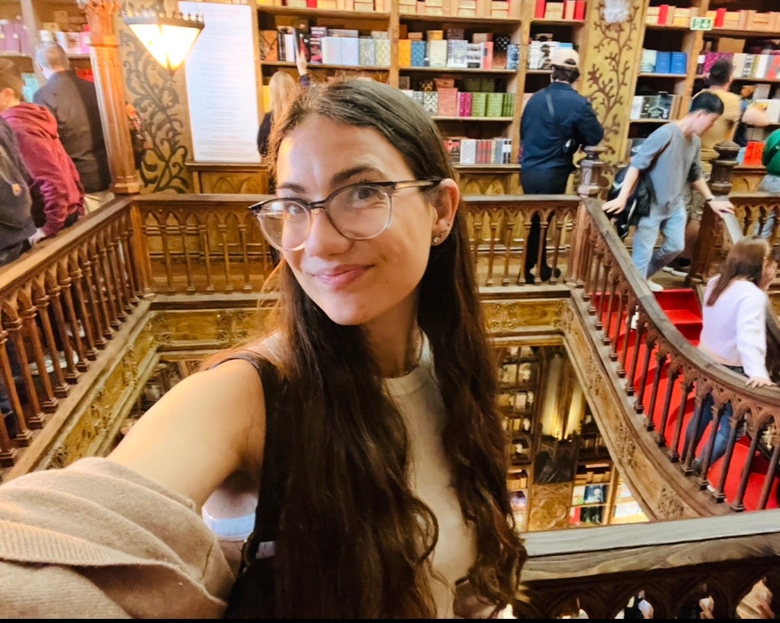 Kayla Melita smiles in a selfie in front of a fancy bookstore