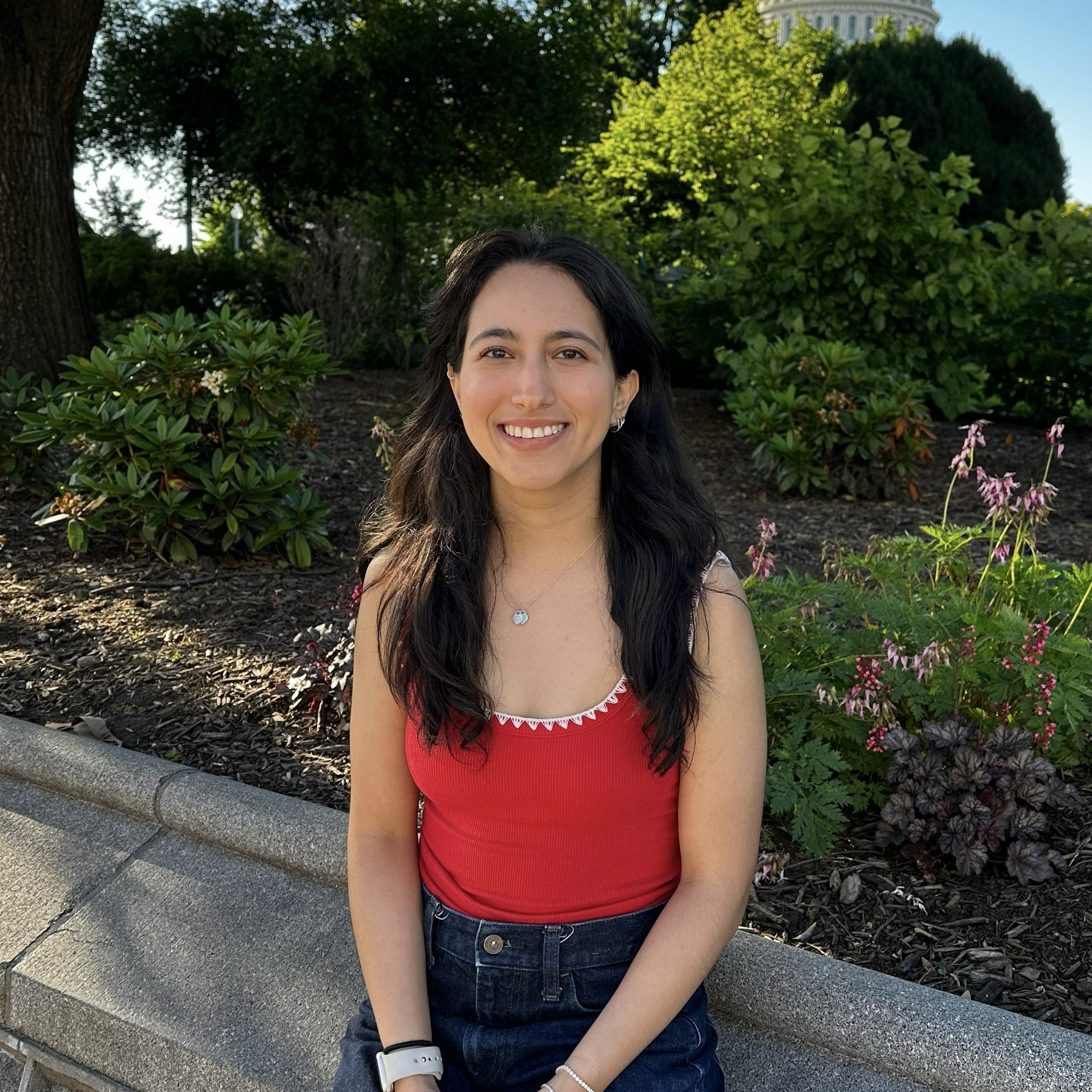 Daniela Yarahuan smiles in a red top and blue jeans, her hair over her shoulders