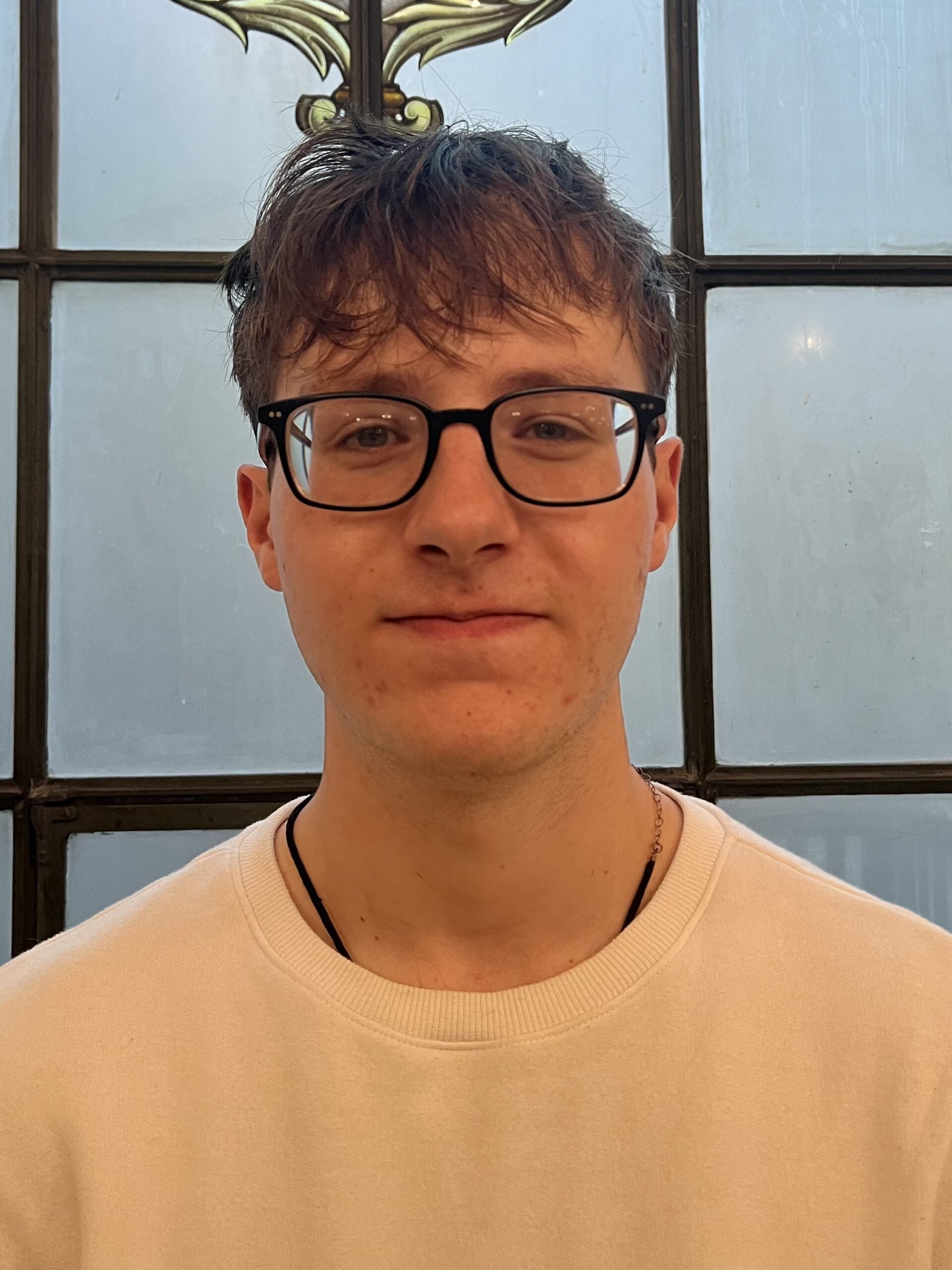 Tim McShea smiles softly at the camera in a white top