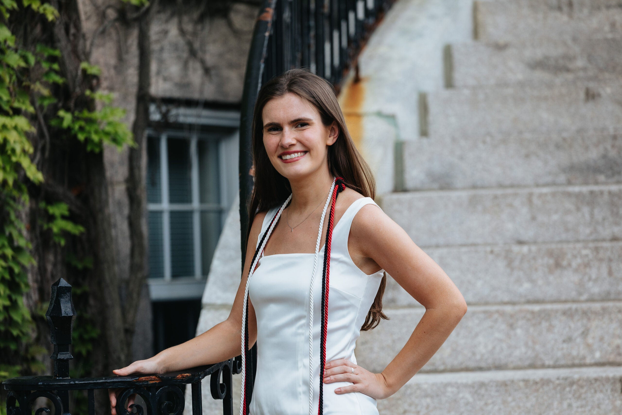 Lizzy Clarke smiles in a white dress and graduation garb
