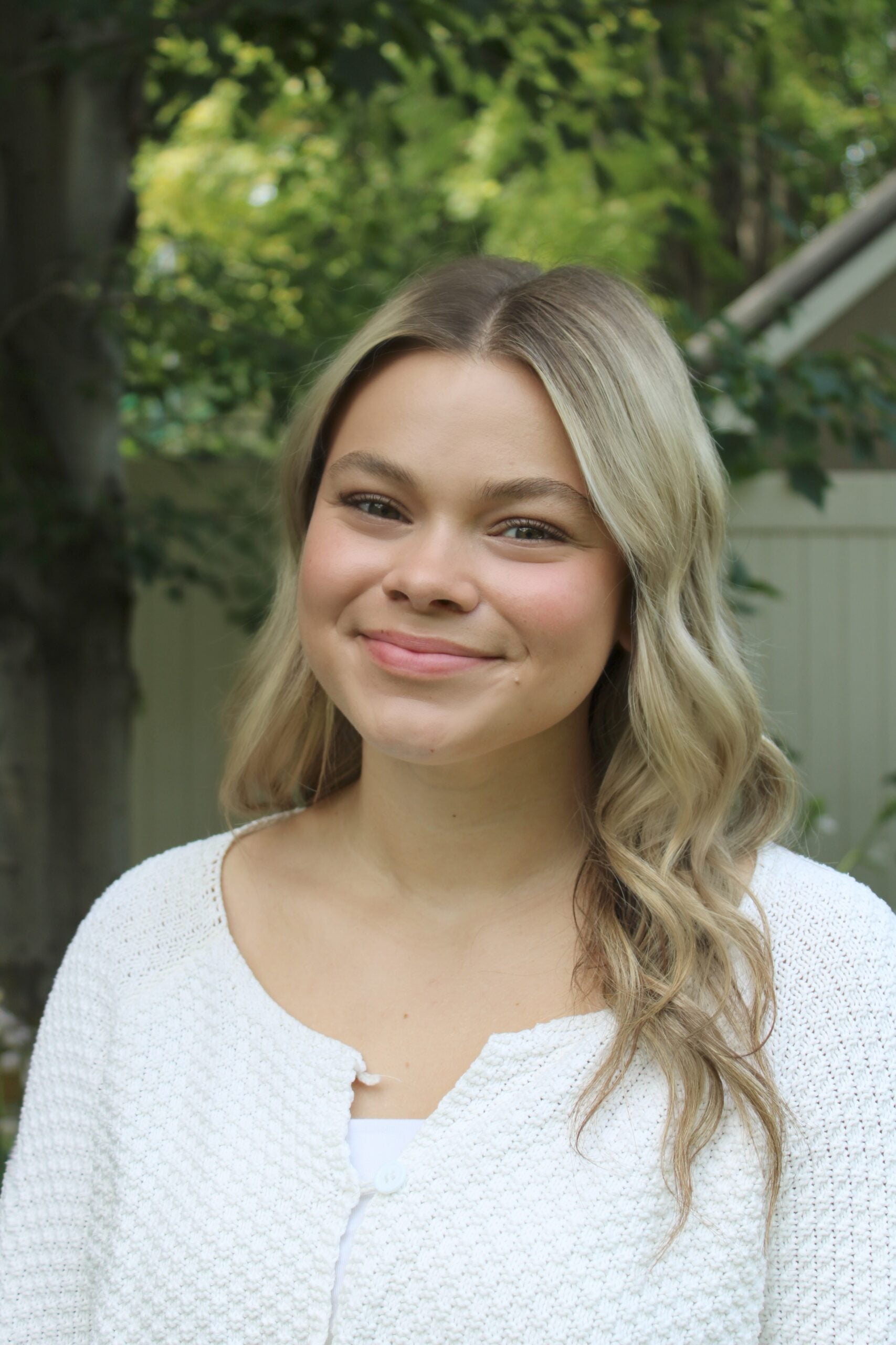 Claire Cunningham smiles at the camera with her blonde hair over one shoulder in a white top