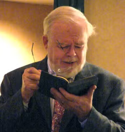 Paul F. Betz holds open a book and reads from it